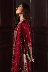 Woman in a red traditional outfit with gold details against a dark background