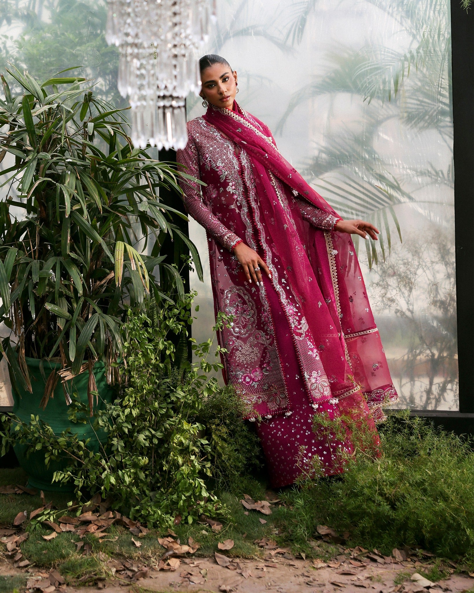 Woman in a pink traditional outfit standing outdoors with greenery around