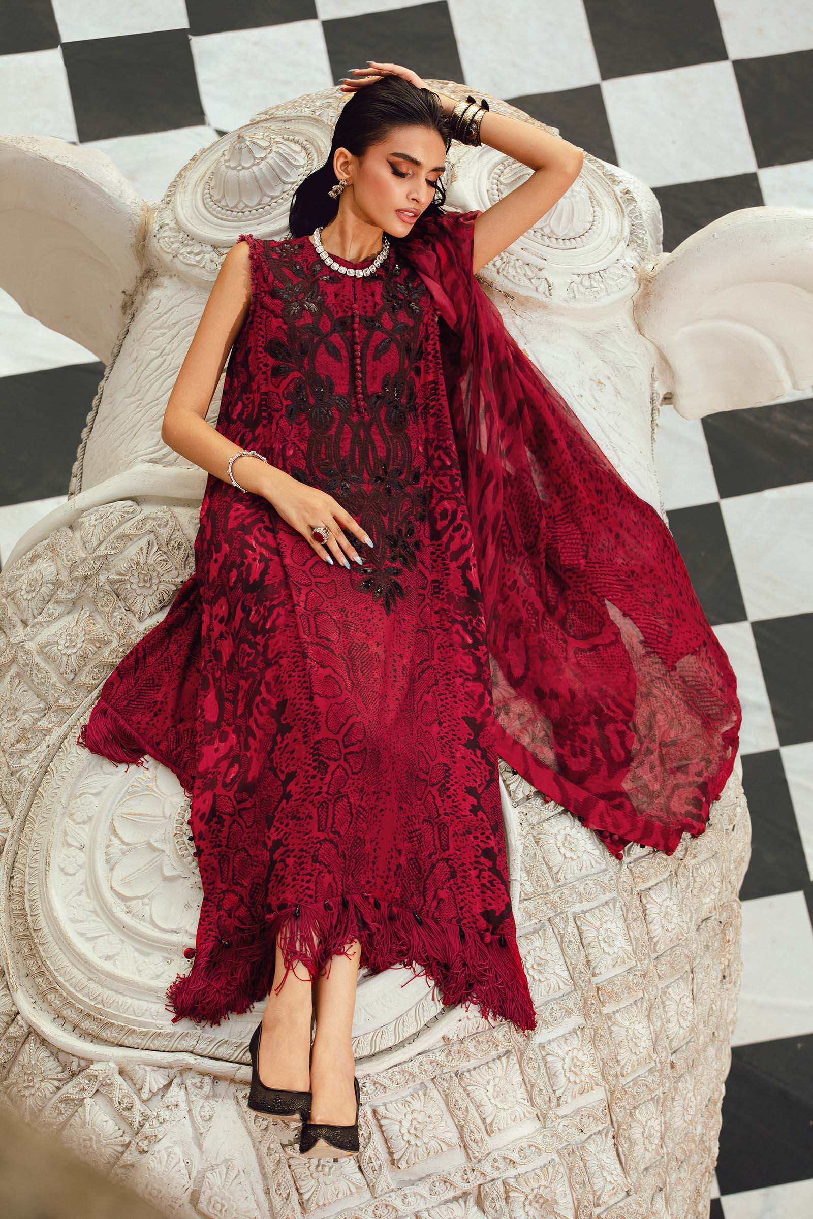 Woman in a red lace dress sitting on an ornate chair with a checkered floor.