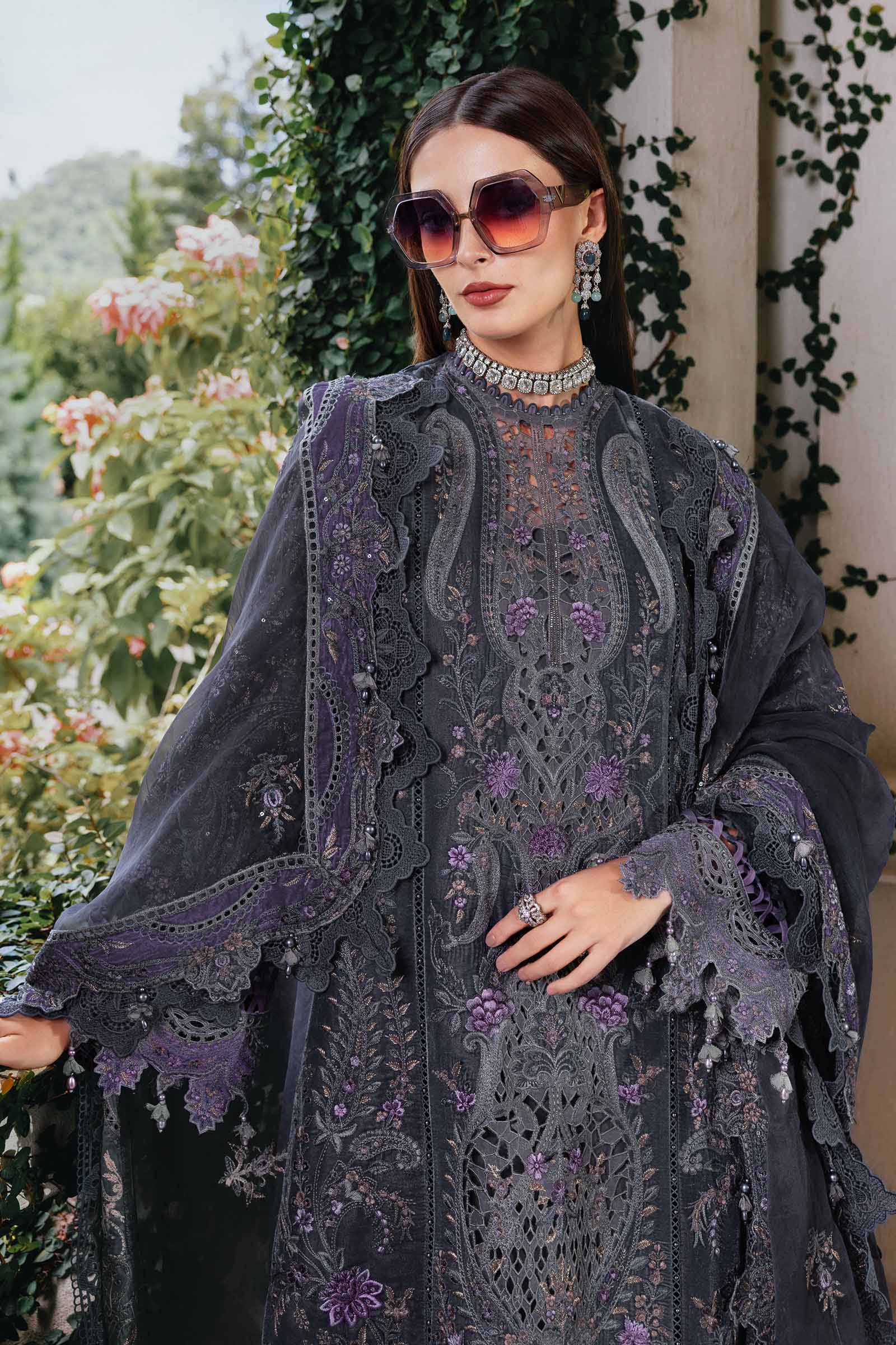 Woman wearing a dark gray embroidered outfit with purple accents outdoors.
