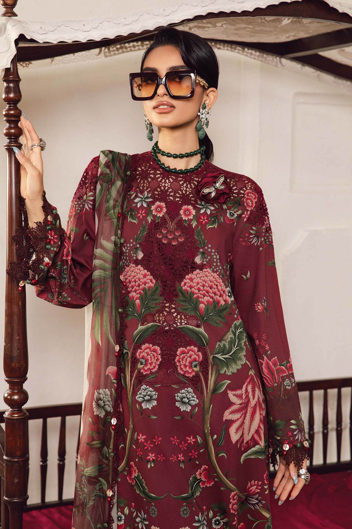 Woman wearing a floral embroidered outfit in a decorated room.