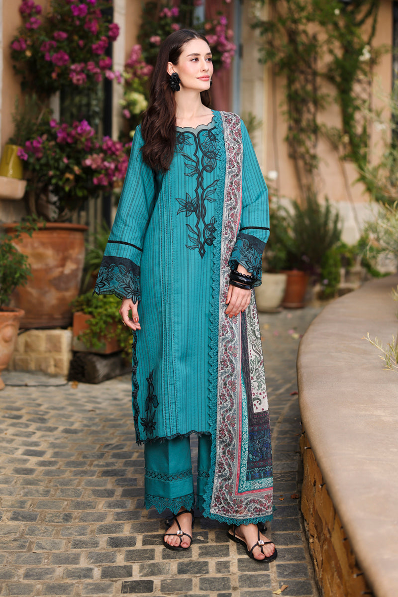 Woman in a teal embroidered outfit standing outdoors with plants in the background